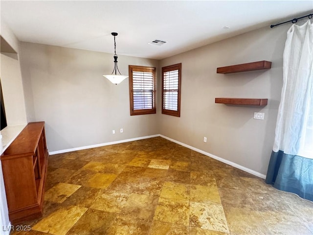 unfurnished dining area featuring baseboards, visible vents, and stone finish flooring