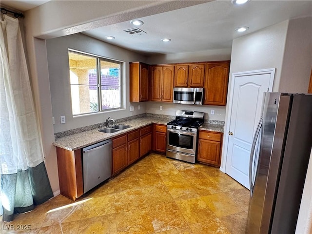 kitchen with appliances with stainless steel finishes, brown cabinetry, visible vents, and a sink