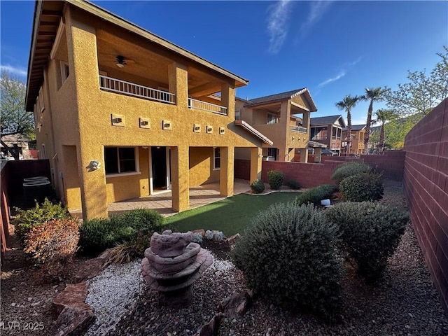 back of house featuring a patio area, a fenced backyard, a balcony, and stucco siding