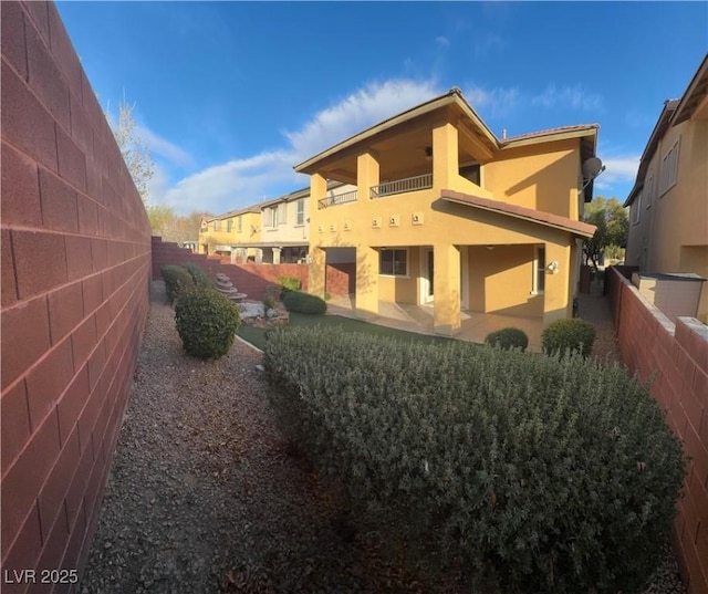 view of side of home with a patio area, a fenced backyard, and stucco siding