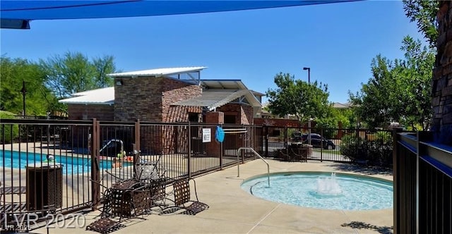 community pool with a patio area and fence