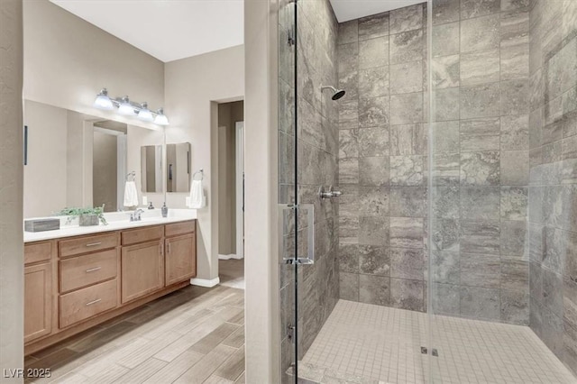 full bathroom featuring a stall shower, vanity, baseboards, and wood finished floors