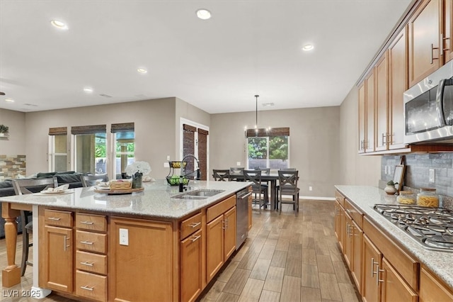 kitchen with a wealth of natural light, decorative backsplash, stainless steel appliances, and a sink