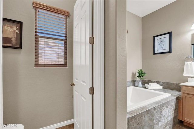 full bathroom with a garden tub, baseboards, wood finished floors, and vanity