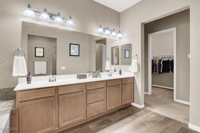 bathroom with a sink, a spacious closet, baseboards, and double vanity