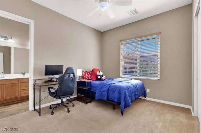 bedroom with baseboards, connected bathroom, visible vents, and light colored carpet