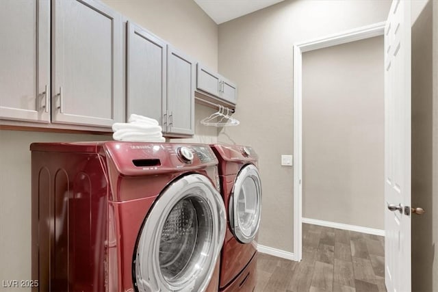 laundry room featuring cabinet space, independent washer and dryer, baseboards, and wood finished floors