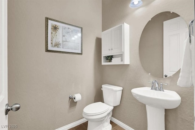 bathroom featuring tile patterned flooring, baseboards, a sink, and toilet