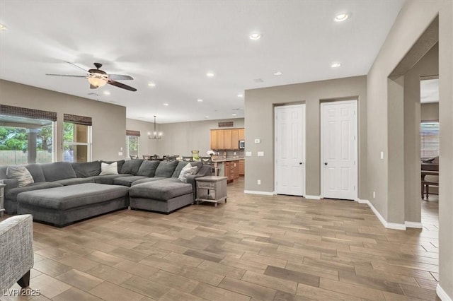 living area featuring baseboards, ceiling fan with notable chandelier, wood tiled floor, and recessed lighting