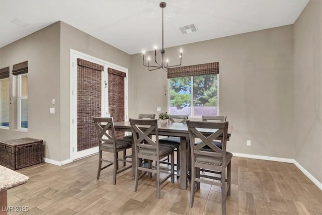 dining room with light wood-style flooring, visible vents, a chandelier, and baseboards