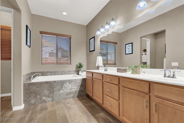 full bath with wood tiled floor, double vanity, a sink, and a bath