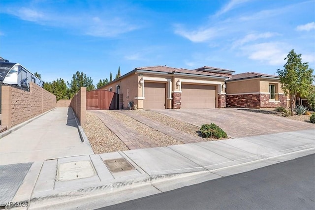 view of front of property with driveway, an attached garage, a gate, and stucco siding