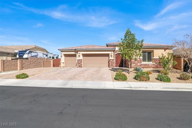 prairie-style home with an attached garage, fence, driveway, stone siding, and stucco siding