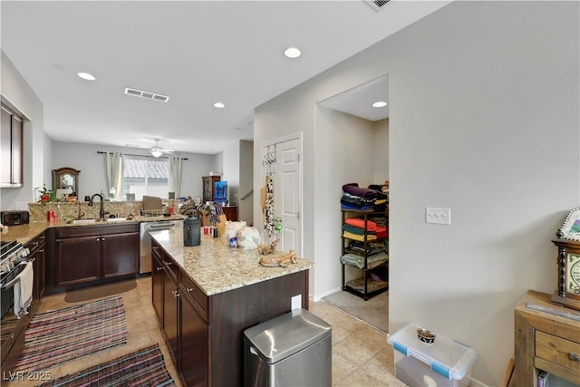 kitchen with visible vents, dark brown cabinetry, a sink, light stone countertops, and dishwasher