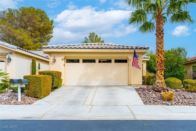 view of front of house with a garage, driveway, a tiled roof, and stucco siding