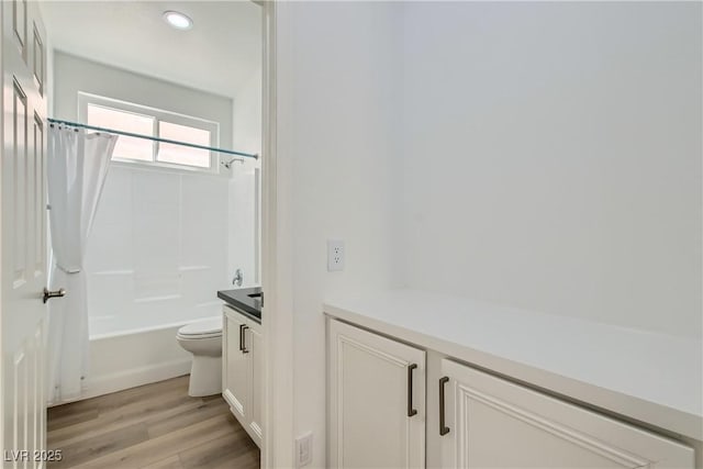 bathroom with toilet, shower / tub combo with curtain, wood finished floors, vanity, and recessed lighting