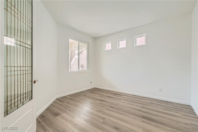 spare room featuring plenty of natural light, light wood-style flooring, and baseboards