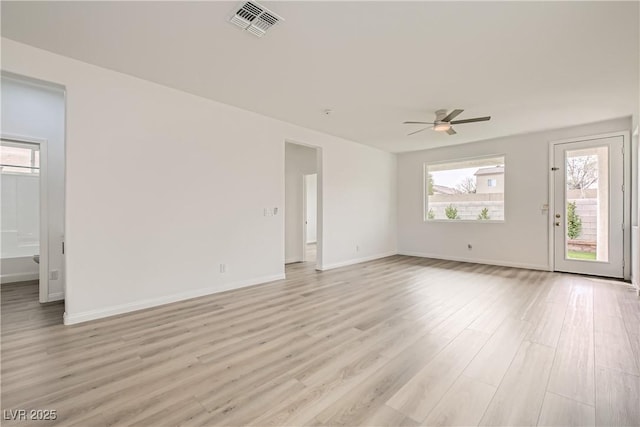 empty room with ceiling fan, light wood-style flooring, visible vents, and baseboards