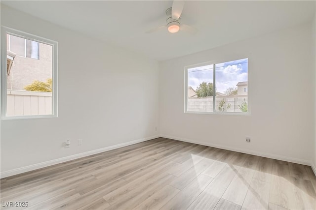 spare room featuring light wood finished floors, ceiling fan, and baseboards