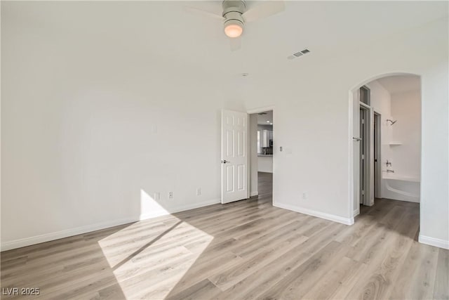 interior space with arched walkways, visible vents, light wood finished floors, and a ceiling fan