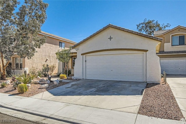 mediterranean / spanish-style home featuring driveway, an attached garage, a tiled roof, and stucco siding