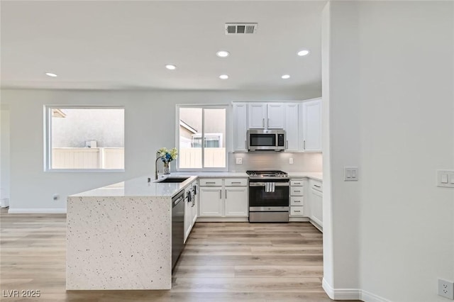 kitchen with light wood-style flooring, visible vents, appliances with stainless steel finishes, and a sink
