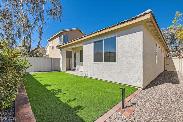 back of property featuring a yard, a fenced backyard, and stucco siding