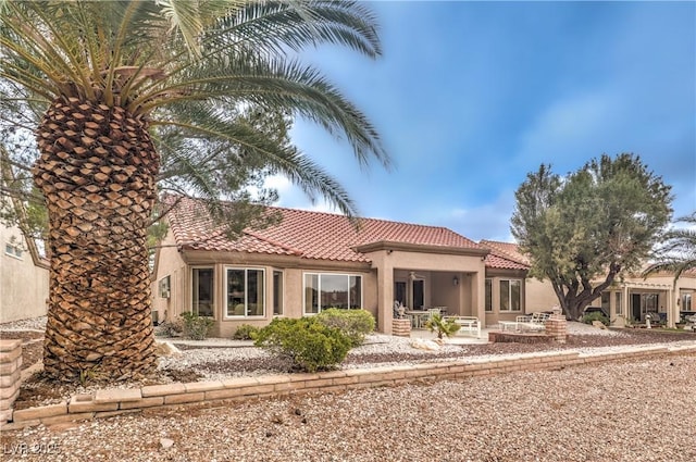 mediterranean / spanish house featuring a patio area, a tile roof, and stucco siding