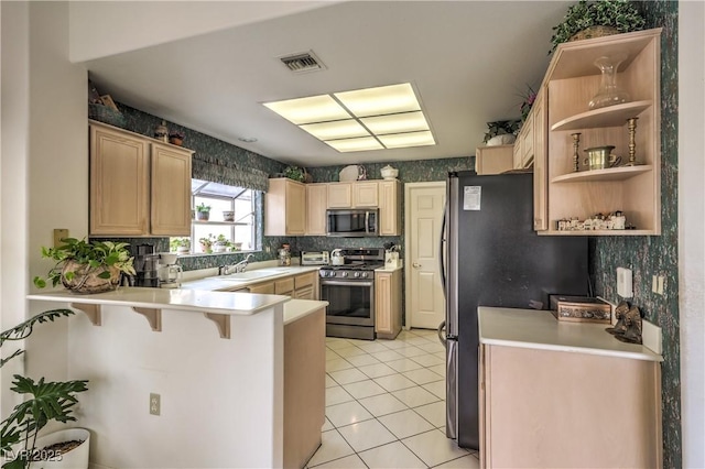 kitchen with appliances with stainless steel finishes, light countertops, a sink, and a peninsula