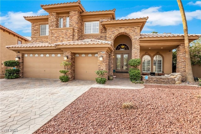 mediterranean / spanish-style house featuring french doors, stucco siding, a garage, stone siding, and driveway