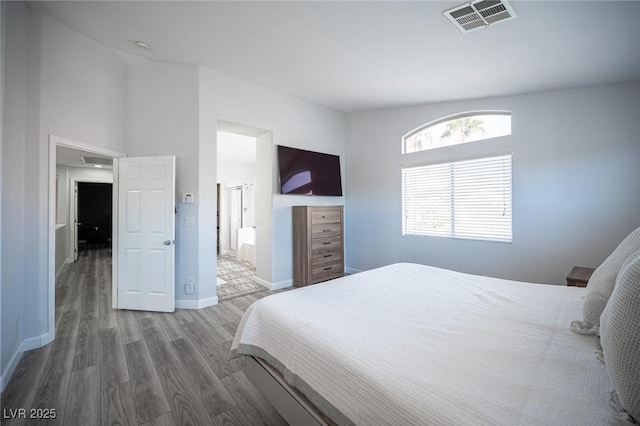 bedroom with baseboards, visible vents, and wood finished floors