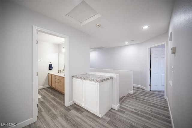 corridor featuring light wood finished floors, attic access, baseboards, and recessed lighting