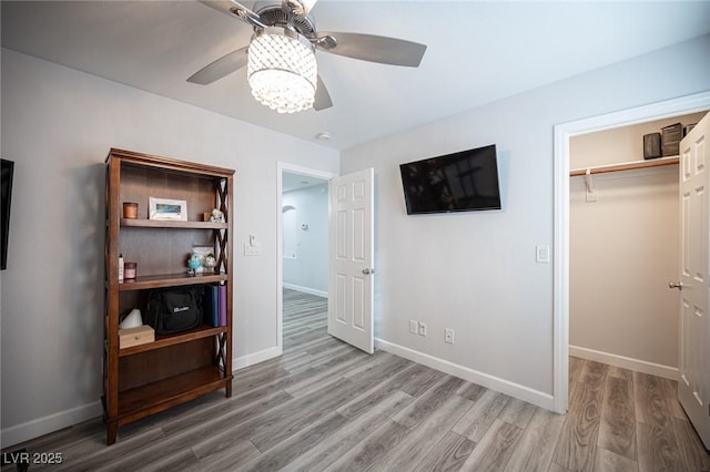 bedroom with a ceiling fan, a closet, light wood-style flooring, and baseboards