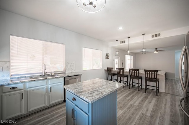 kitchen with appliances with stainless steel finishes, visible vents, a sink, and wood finished floors