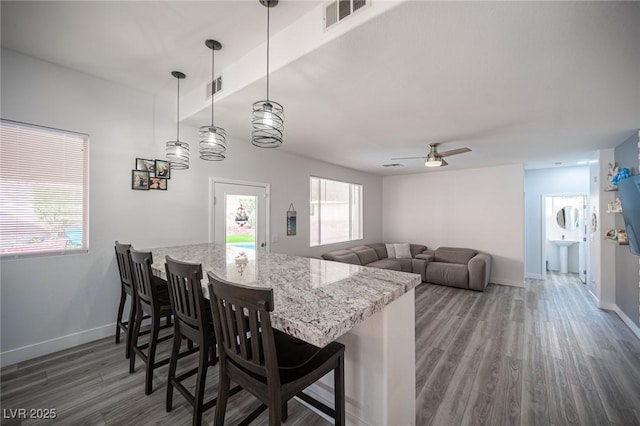 kitchen featuring baseboards, wood finished floors, visible vents, and a kitchen breakfast bar