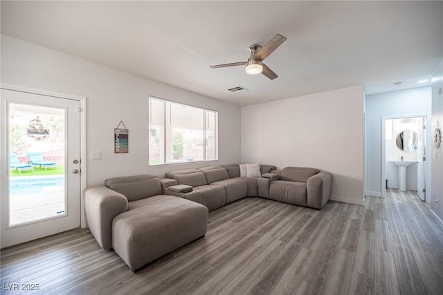 living area with visible vents, ceiling fan, and wood finished floors