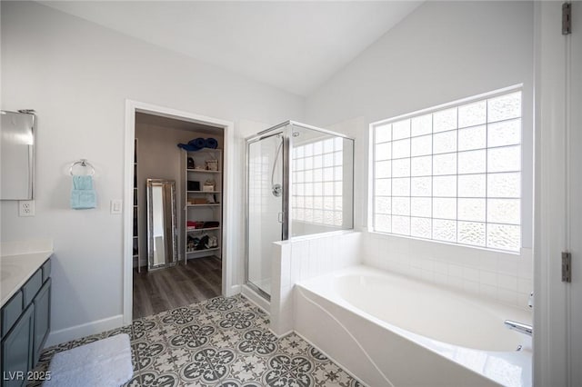 full bath with lofted ceiling, a spacious closet, vanity, a shower stall, and a bath