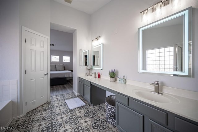 full bathroom featuring a washtub, double vanity, a sink, and tile patterned floors