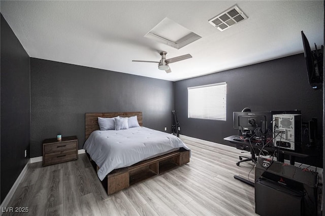 bedroom featuring a ceiling fan, baseboards, visible vents, and wood finished floors