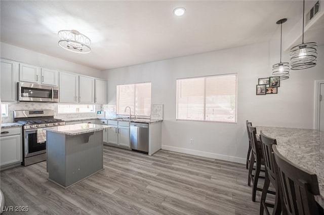 kitchen with visible vents, decorative backsplash, appliances with stainless steel finishes, a breakfast bar area, and light wood-type flooring