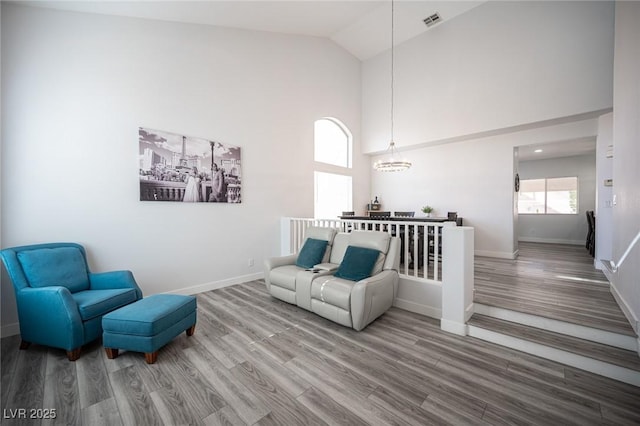 living room with high vaulted ceiling, wood finished floors, visible vents, and baseboards