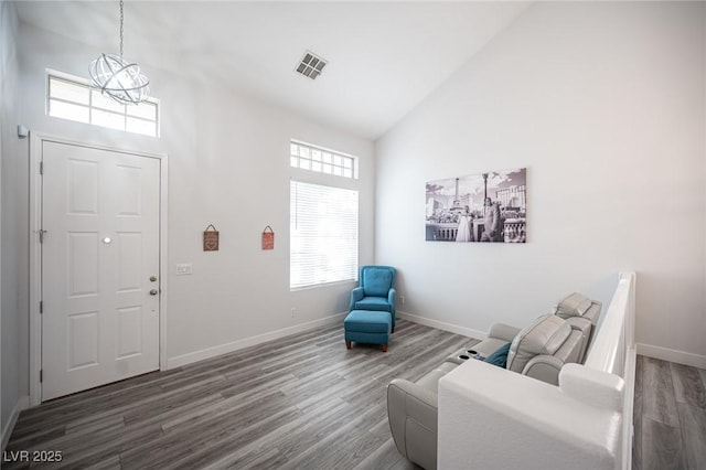 living area featuring baseboards, visible vents, a chandelier, wood finished floors, and high vaulted ceiling