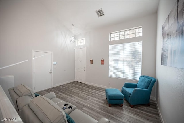 living area featuring a healthy amount of sunlight, baseboards, visible vents, and wood finished floors