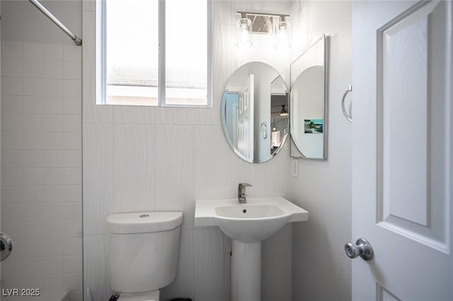 full bath featuring washtub / shower combination, toilet, and a ceiling fan