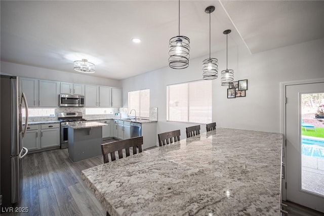 kitchen with dark wood finished floors, a breakfast bar area, a center island, stainless steel appliances, and a sink