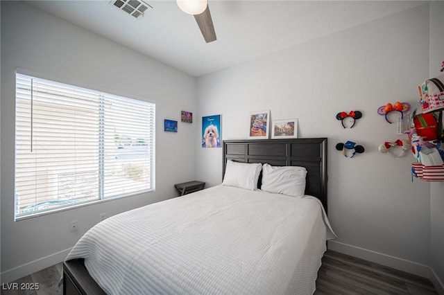 bedroom with a ceiling fan, visible vents, baseboards, and wood finished floors