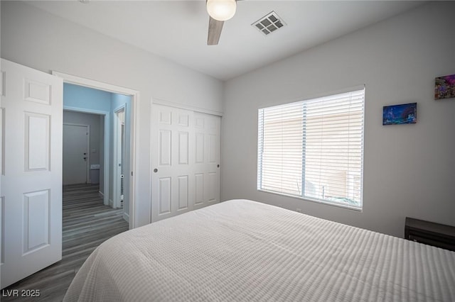 bedroom featuring dark wood-type flooring, a closet, visible vents, and a ceiling fan