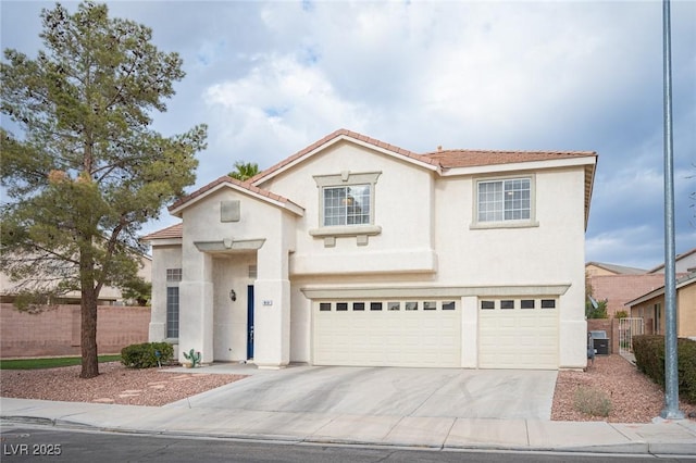 mediterranean / spanish-style home with a garage, fence, and stucco siding