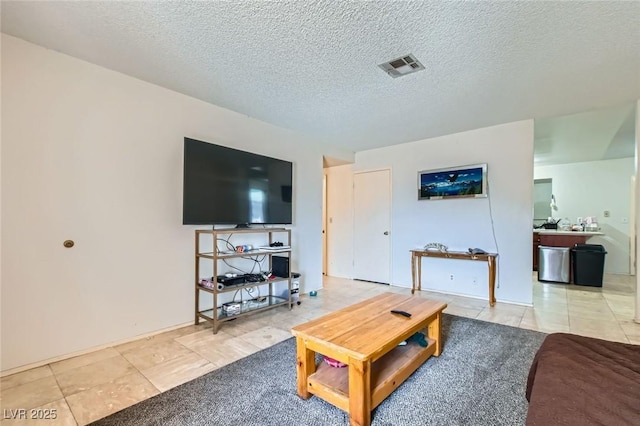 living room with visible vents, a textured ceiling, and light tile patterned floors