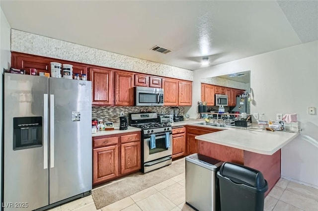 kitchen with light tile patterned floors, visible vents, appliances with stainless steel finishes, a peninsula, and backsplash